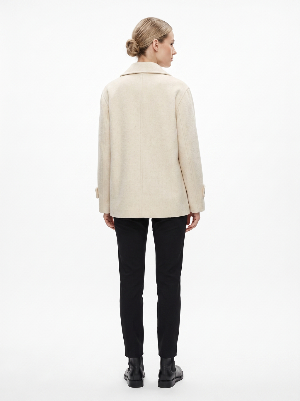 Kvinde i en creme kort oversized uldfrakke set bagfra i helfigur, fotograferet i studie mod hvid baggrund — Bjerrelund