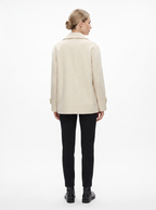 Kvinde i en creme kort oversized uldfrakke set bagfra i helfigur, fotograferet i studie mod hvid baggrund — Bjerrelund