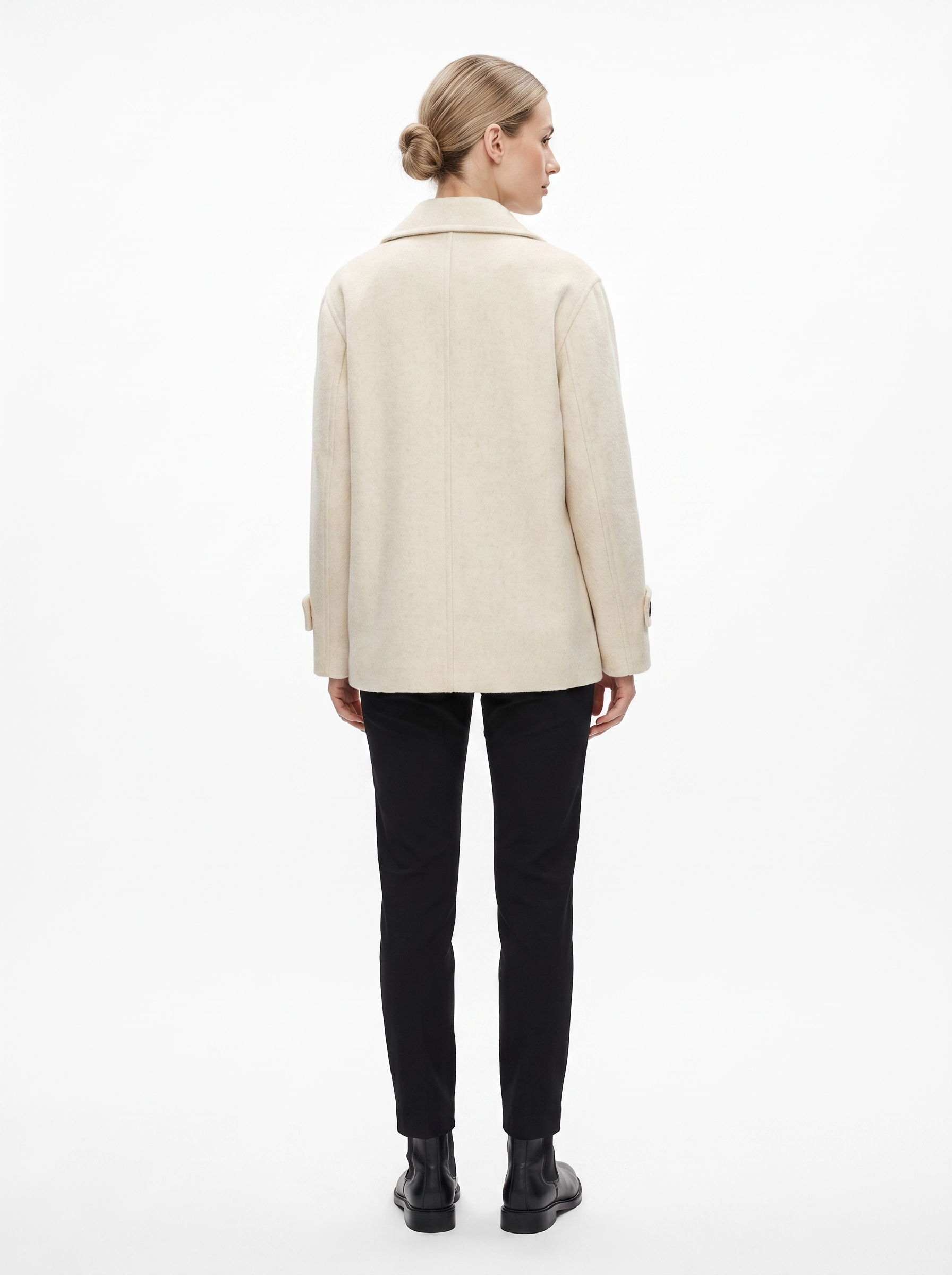 Kvinde i en creme kort oversized uldfrakke set bagfra i helfigur, fotograferet i studie mod hvid baggrund — Bjerrelund