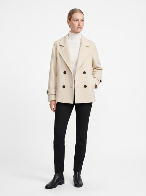 Kvinde i en creme kort oversized uldfrakke set forfra i helfigur, fotograferet i studie mod hvid baggrund — Bjerrelund