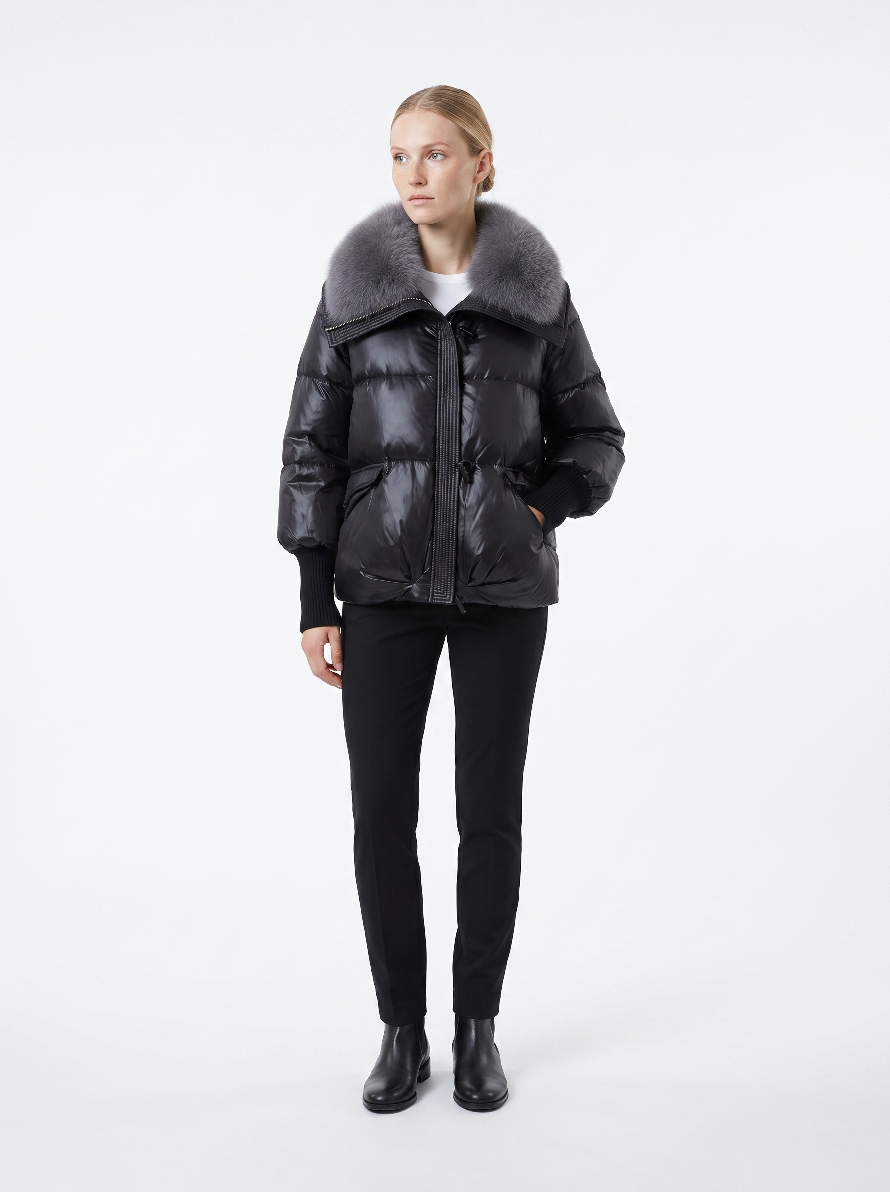 Kvinde i en sort kort dunjakke med pelskrave set forfra i helfigur mod hvid baggrund — Bjerrelund